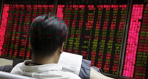 An investor looks at a newspaper in front of an electronic board showing stock information at a brokerage house in Beijing, August 27, 2015. China's turbulent stock markets rose on Thursday, helped by a strong rebound on Wall Street on expectations that the U.S. Federal Reserve will respond to days of China-led volatility by delaying an expected interest rate rise next month. REUTERS/Jason Lee