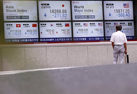 A man looks at screens displaying market indices at a brokerage in Tokyo, August 25, 2015. Asian stocks looked vulnerable to another sell-off on Tuesday, with investors gripped by fears of a hard landing for the Chinese economy, the world's most important growth engine. REUTERS/Thomas Peter