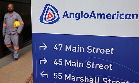 A worker walks past a board outside Anglo American offices in Johannesburg. REUTERS/Siphiwe Sibeko