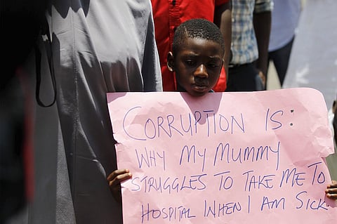 A boy holds a placard during a rally in support of President Muhammadu Buhari's anti-corruption campaign, at the gate of the presidential villa in Abuja, Nigeria August 17, 2015. Buhari has appointed a committee to advise him on the best way to tackle corruption and reform the legal system, his spokesman said last Monday. Buhari, who took office on May 29 after being elected on promises to fight endemic corruption, has said he believes officials have stolen around $150 billion from the public purse over the past decade. REUTERS/Afolabi Sotunde