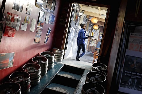 A woman carries beer produced by brewing company SAB Miller past kegs at a bar in Cape Town, September 16, 2015. Anheuser-Busch InBev has approached rival SABMiller about a takeover that would form a brewing colossus producing a third of the world's beer. A merged group would have a market value of around $275 billion (£177 billion) at current prices, and would combine AB InBev's dominance of Latin America with SABMiller's dominance in Africa, both fast-growing markets, as well as their breweries in Asia. REUTERS/Mike Hutchings