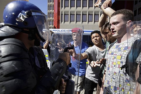 Students protest over planned increases in tuition fees outside South Africa's Parliament in Cape Town, October 21, 2015. Riot police fired tear gas and stun grenades on Wednesday at hundreds of protesting students who stormed the parliament precinct in Cape Town to try to disrupt the reading of Finance Minister Nhlanhla Nene's interim budget. REUTERS/Mark Wessels