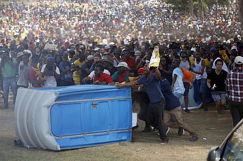 Protesters push a portable loo before burning it during a protest over planned increases in tuition fees outside the Union building in Pretoria, South Africa October 23, 2015. South African police fired stun grenades at students who lit fires outside President Jacob Zuma's offices following a week of protests, the first signs of the post-apartheid 'Born Free' generation flexing its muscle. REUTERS/Siphiwe Sibeko