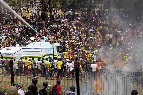 File Photo. A demonstrator hangs on to a police water cannon during a protest over planned increases in tuition fees outside the Union building in Pretoria, South Africa October 23, 2015. South African police fired stun grenades at students who lit fires outside President Jacob Zuma's offices following a week of protests, the first signs of the post-apartheid 'Born Free' generation flexing its muscle. REUTERS/Siphiwe Sibeko