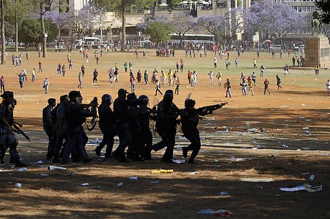 Protesters run as they are dispersed by police officers during a protest over planned increases in tuition fees outside the Union building in Pretoria, October 23, 2015. South African police fired stun grenades and used water cannon to douse fires lit by students protesting on the grounds of the buildings where President Jacob Zuma has his offices, a Reuters witness said. REUTERS/Siphiwe Sibeko
