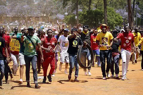 Demonstrators gesture at a photographer during a protest over planned increases in tuition fees outside the Union building in Pretoria, South Africa October 23, 2015. South African police fired stun grenades at students who lit fires outside President Jacob Zuma's offices following a week of protests, the first signs of the post-apartheid 'Born Free' generation flexing its muscle. REUTERS/Siphiwe Sibeko‚Ä®