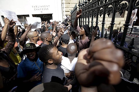 Students protest over planned increases in tuition fees outside South Africa's Parliament in Cape Town, October 21, 2015. Riot police fired tear gas and stun grenades on Wednesday at hundreds of protesting students who stormed the parliament precinct in Cape Town to try to disrupt the reading of Finance Minister Nhlanhla Nene's interim budget. REUTERS/Mark Wessels