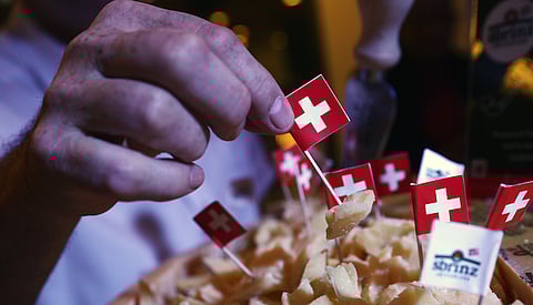 An attendee samples Swiss cheese using a cocktail stick with a mini Swiss national flag on it during a closing day buffet at the World Economic Forum (WEF) in Davos, Switzerland, on Saturday, Jan. 23, 2016. World leaders, influential executives, bankers and policy makers attend the 46th annual meeting of the World Economic Forum in Davos from Jan. 20 - 23. Photographer: Simon Dawson/Bloomberg