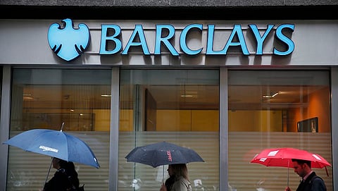 Pedestrians shelter under umbrellas as they walk past a Barclays bank branch in central London, in this file photograph dated May 8, 2014. Barclays Plc is to exit its business in Africa as part of plans to simplify the group and boost shareholder returns after reporting on March 1, 2016 a 2 percent fall in full-year profit. REUTERS/Stefan Wermuth/files