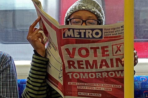 A woman reads a newspaper on the underground in London with a 'vote remain' advert for the BREXIT referendum, Britain June 22, 2016. REUTERS/Russell Boyce