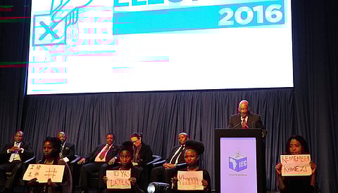 South Africa's President Jacob Zuma (2nd R) makes a speech as protesters hold placards in front of him during the official announcement of the munincipal election results at the result centre in Pretoria, South Africa, August 6, 2016. The placards refer to Khwezi, a woman whom Zuma was acquitted of raping by a court in 2006. The protesters were later removed by security. REUTERS/Stringer