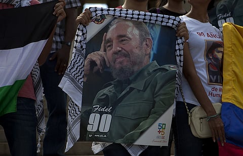 People hold signs and flags outside of Habana University as they react to news of the death of Fidel Castro, former Cuban president, in Havana, Cuba, on Saturday, Nov. 26, 2016. Castro, who established a communist regime in Cuba that survived the collapse of the Soviet Union, inspired revolutionary movements and brought two superpowers close to nuclear war before stepping down after 49 years in power, has died. He was 90. Photographer: Eliana Aponte/Bloomberg