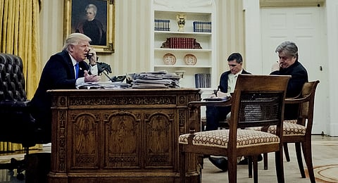 U.S. President Donald Trump, left, speaks on the phone with Malcolm Turnbull, Australia's prime minister, as retired Lieutenant General Michael Flynn, U.S. national security advisor, center, and Steve Bannon, chief strategist for U.S. President Donald Trump, wait during the first official phone talks in the Oval Office of the White House in Washington, D.C., U.S., on Saturday, Jan. 28, 2017. Turnbull is confident the new U.S. administration will uphold an agreement to resettle asylum seekers held on Pacific island camps. Photographer: Pete Marovich/Pool via Bloomberg