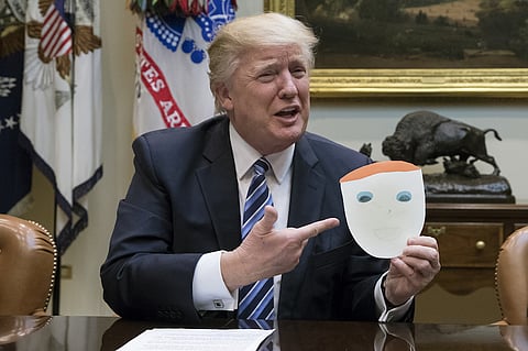 U.S. President Donald Trump holds up a drawing made by a child of an attendee during a meeting on health care in the Roosevelt Room of the White House in Washington, D.C., U.S., on Monday, March 13, 2017. Senate Democrats warned Republicans Monday that attempts to take funding away from Planned Parenthood or pay for Trump's border wall in a stopgap spending bill that must pass by late April would result in a government shutdown. Photographer: Michael Reynolds/Pool via Bloomberg