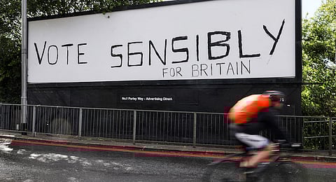 A cyclist passes a graffitied sign, painted onto a billboard, urging people to "Vote Sensibly for Britain" at a traffic interchange in Croydon, south London, U.K., on Tuesday, June 6, 2017. Theresa May said she'd be willing to tear up human-rights legislation to combat terrorism in a move the Labour opposition said was an attempt to distract from her cuts to police, as security dominated the closing stages of the U.K. election campaign. Photographer: Luke MacGregor/Bloomberg