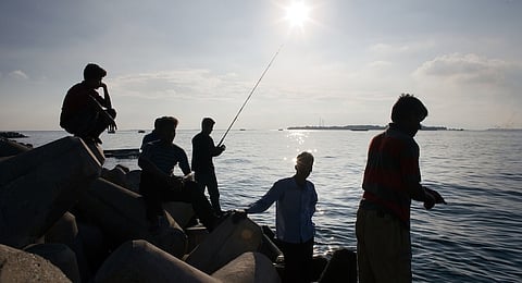 Men fish and relax near a seawall in Male, the Maldives. Photographer: DANIEL J. GROSHONG/Bloomberg
