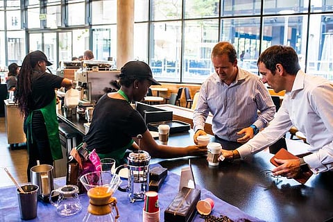 A barista serves customers their beverages at the pick-up counter inside a Starbucks Corp. cafe in the Sandton area of Johannesburg, South Africa, on Monday, Jan. 14, 2019. While South Africa's economy emerged from a recession in the third quarter, growth remains sluggish, hampered by subdued business confidence, higher taxes imposed by the government in February and a tight monetary-policy stance. Photographer: Waldo Swiegers/Bloomberg