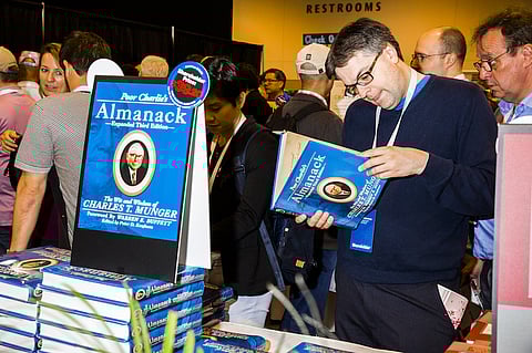 An attendee views a copy of the book "Poor Charlie's Almanack" during a shareholders shopping day ahead of the Berkshire Hathaway annual meeting in Omaha, Nebraska, U.S., on Friday, May 4, 2018. Berkshire Hathaway Inc. investors should get ready for a bumpy ride. Warren Buffett's company is scheduled to report earnings Saturday morning before its annual meeting, and a new accounting rule could sink results. Photographer: David Williams/Bloomberg