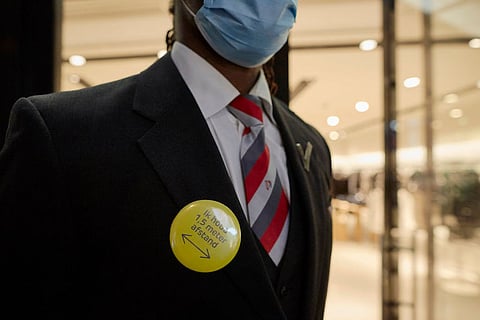 ROTTERDAM, NETHERLANDS - NOVEMBER 28: A security worker wears a badge asking people to keep 1,5 meter distance as The Netherlands implements new measures of a soft evening lockdown to counter the Coronavirus pandemic on November 28, 2021 in Rotterdam, Netherlands. For at least the next three weeks, venues such as cafes, museums, and cinemas must close by 5pm, and remain closed until 5am. 13 cases of infections by the Omicron variant have been detected by travelers flying back to The Netherlands from South Africa. (Photo by Pierre Crom/Getty Images)