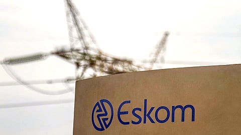 An electricity pylon stands beyond an Eskom sign at the entrance to the Grootvlei power station, operated by Eskom Holdings SOC Ltd., in Grootvlei, South Africa. Photographer: Dean Hutton/Bloomberg