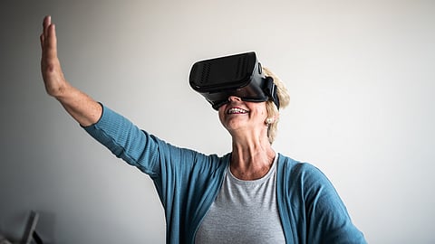 Happy senior woman wearing virtual reality simulator