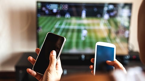 Friends using mobile phone during a tennis match on the TV.