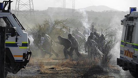 MARIKANA, SOUTH AFRICA - AUGUST 16: (SOUTH AFRICA OUT) Police officers open fire on striking mine workers outside the Nkageng informal settlement on August 16, 2012 in Marikana, South Africa. 30 people are reported to have been killed in the shootings. Violence broke out in the area as workers downed tools at the the Lonmin Marikana Platinum Mine during a wage strike heightened by disputes between the established National Union of Mineworkers (NUM) and the newly formed Association of Mineworkers and Construction Union (AMCU). (Photo by Felix Dlangamandla/Foto24/Gallo Images/Getty Images)