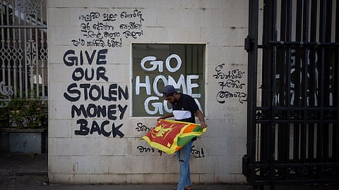 A protester unfurls the Sri Lankan national flag at the vandalized gateway of the presidential palace on July 13, 2022 in Colombo, Sri Lanka. Sri Lanka’s airforce has confirmed that President Gotabaya Rajapaksa has fled the country on a military jet to the Maldivian capital Male, following days of unrest in which the presidential palace and office were taken over by anti-government protesters. (Photo by Abhishek Chinnappa/Getty Images)