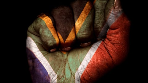 Image of a dirty clenched fist with the flag of South Africa painted on it.
