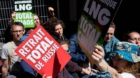 An environmental activists hold up a placard which reads "Total Withdrawal From Russia" while protesting outside the venue of the TotalEnergies SE annual general meeting in Paris, France, on Wednesday, May 25, 2022. Climate activists disrupted the meeting by blocking the entrance to denounce the company's environmental policies and stake in Russia despite Moscow's war in Ukraine. Photographer: Benjamin Girette/Bloomberg