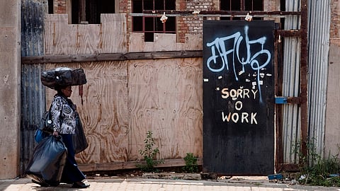 A hawker carries her wares past a 'no work' sign in an economically depressed area near Johannesburg's central business district, South Africa, Wednesday, March 3, 2008. Photographer: Nadine Hutton/Bloomberg News