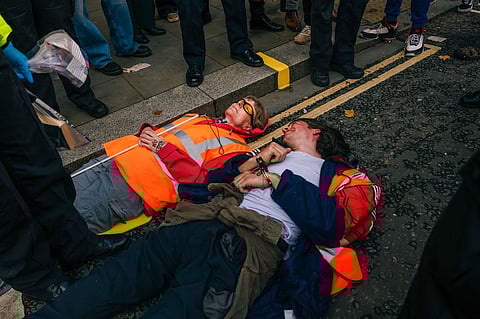 Activists from the "Just Stop Oil" environmental coalition attempt to block a road during a sit-in protest in London, UK, on Thursday, Oct. 27, 2022. The coalition of groups are pushing for the government to commit to halting new fossil fuel licensing and production. Photographer: Jose Sarmento Matos/Bloomberg