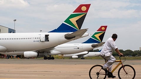 A man cycles past Airbus Group NV A340, left, and A330-200 aircraft operated by South African Airways at OR Tambo International airport in Johannesburg, South Africa. Photographer: Waldo Swiegers/Bloomberg