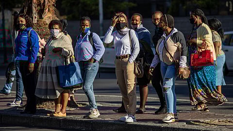 Commuters wearing protective face masks wait to cross Strand Street outside the 'Cape Town Station' Metrorail Station in Cape Town, South Africa, on Monday, Jan. 11, 2021. The pandemic and restrictions imposed to contain it have devastated Africa's most industrialized economy, and the extension of curbs that came into effect at the height of the holiday season bode ill for efforts to engineer a rebound. Photographer: Dwayne Senior/Bloomberg