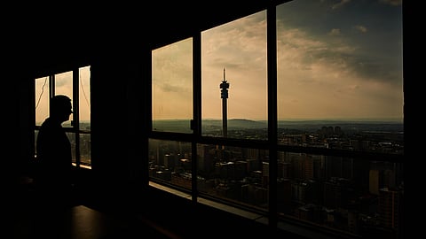 A visitor looks out towards the Telkom Tower and city skyline from the Ponte City Apartments building in the Berea district of Johannesburg, South Africa, on Thursday, Dec. 22, 2022. Johannesburg, South Africas economic hub and its richest city, is seeking electricity supply from private generators to reduce the amount of scheduled power outages. Photographer: Waldo Swiegers/Bloomberg