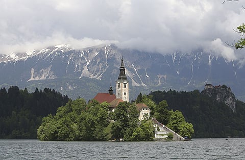 The church of the Assumption of Mary, a pilgrimage site and tourist attraction, is seen beneath the Julian Alps on Lake Bled, Slovenia. Source: Bloomberg