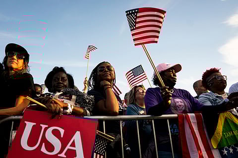 Attendees hold signs and American flags prior to a campaign event with Kamala Harris.