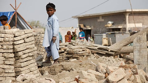 Extreme events aren’t ‘natural’ at all: A child stands amongst the remains of buildings destroyed by the floods in Pakistan