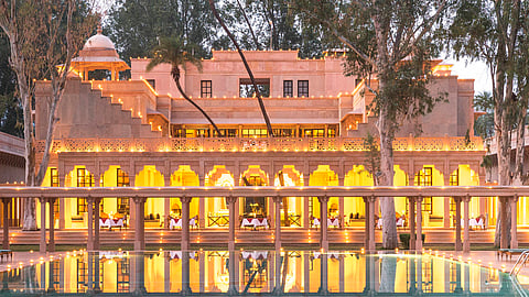 A dining set-up reflected in the pool at Amanbagh