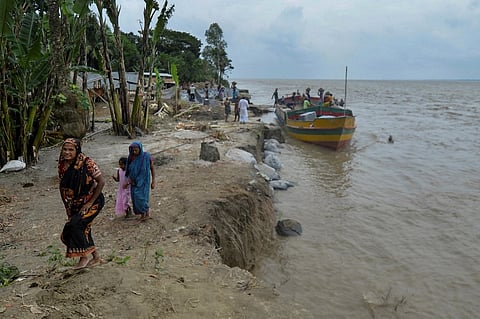 In this picture taken on 20 September
2021, locals walk past an eroded section on the banks of river Padma in Manikgonj. Bangladesh, a low-lying nation of crisscrossing muddy rivers at the top of the Bay of Bengal, has long been battered by nature. (Photo by MUNIR UZ ZAMAN / AFP)