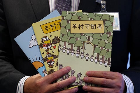 In this file photo, Hong Kong's senior superintendent Steve Li, from the city's new national security police unit, holds children's books which allegedly try to explain about the city's democracy movement, at a police press conference in Hong Kong on 22 July 2021, after five members of a pro-democracy Hong Kong union were arrested for sedition for publishing the titles. (Photo by DANIEL SUEN / AFP)