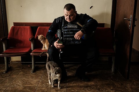 A police officer uses his smartphone at the lobby of the local civil administration office in the retaken town of Kozacha Lopan, Kharkiv region, on 20 September 2022. A sweeping Ukrainian counter-offensive in recent weeks has seen Kyiv's forces retake hundreds of towns and villages that had been controlled by Russia for months. (Photo by YASUYOSHI CHIBA / AFP)
