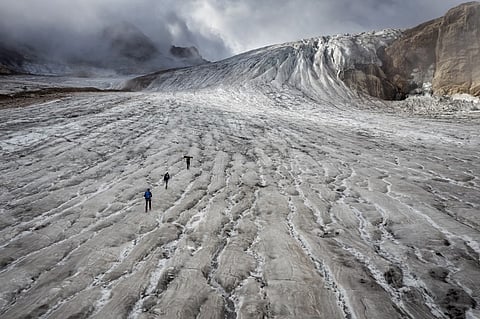 This picture taken on 2 September 2022 above Ulrichen shows glaciologist and head of Glacier Monitoring in Switzerland network Matthias Huss and his team on the Gries glacier to take readings of measuring equipment. Swiss glaciers smashed all records for melting in 2022, under the dual effect of a dry winter and a long wave of intense summer heat. (Photo by FABRICE COFFRINI / AFP)