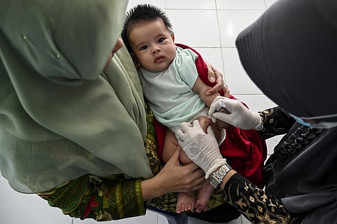 A baby receives a Bacillus Calmette-Guerin vaccine for tuberculosis during a national immunization for children program at an integrated services post in Banda Aceh on 9 June 2022. (Photo by CHAIDEER MAHYUDDIN / AFP)