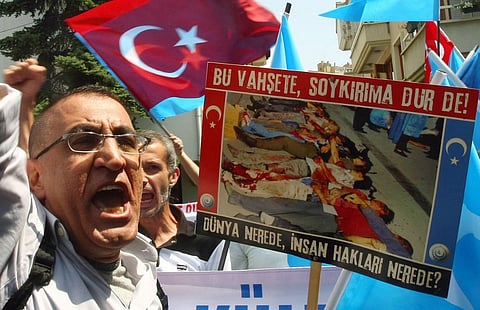 A Uighur living in Turkey holds a banner reading ''Stop the violence, stop the genocide!, Where is the world, where's human rights?'' as he takes part in a demonstration outside the Chinese embassy in Ankara on 22 July 2011 to protest against alleged Chinese brutality against members of the Chinese Muslim Uighur minority in China's far-western Xinjiang Region. (Photo by ADEM ALTAN / AFP)