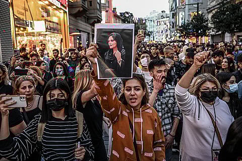 A protester holds a portrait of Mahsa Amini during a demonstration in support of Amini, a young Iranian woman who died after being arrested in Tehran by the Islamic Republic's morality police, on Istiklal avenue in Istanbul on September 20, 2022. - Amini, 22, was on a visit with her family to the Iranian capital when she was detained on September 13 by the police unit responsible for enforcing Iran's strict dress code for women, including the wearing of the headscarf in public. She was declared dead on September 16 by state television after having spent three days in a coma. (Photo by Ozan KOSE / AFP)