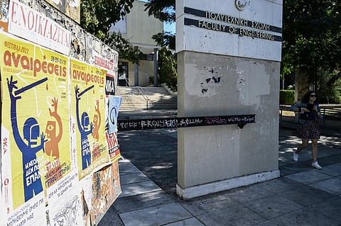 This picture taken on 29 September shows a student walking by banners against government plans to introduce policing on university campuses, in Thessalonikis Aristotelio university. - Over a year after it was conceived as a groundbreaking response to Greece's notoriously unruly universities, a special campus police force was officially deployed this month. Photo by Sakis MITROLIDIS / AFP