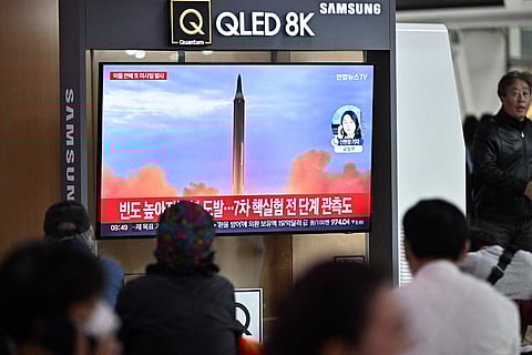 People sit near a television showing a news broadcast with file footage of a North Korean missile test, at a railway station in Seoul on 6 October. -Photo by Anthony WALLACE / AFP