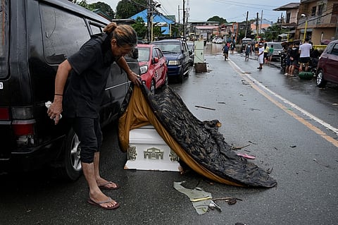 A man lifts the cover of a coffin that was swept away by flood due to heavy rains brought by Tropical Storm Nalgae in Kawit, Cavite province on October 30, 2022. Photo by JAM STA ROSA / AFP