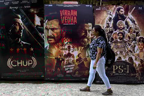 In this picture taken on 1 October 2022, a moviegoer walks past movie posters displayed outside the G7 multiplex in Mumbai. India's Bollywood film industry, long part of the cultural fabric of the movie-mad country of 1.4 billion people, is facing its biggest-ever crisis as streaming services and non-Hindi language rivals steal its sparkle. (Photo by PUNIT PARANJPE / AFP)